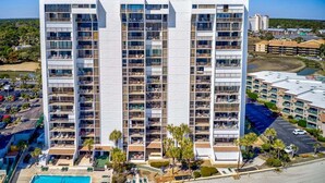 A multi-story hotel with balconies, a swimming pool, and a parking area. - Oceanfront 5th floor,quiet,peaceful.beautiful views (Myrtle Beach)
