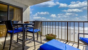 A balcony with a table and chairs, a sofa, and a view of the beach and ocean. - Oceanfront 5th floor,quiet,peaceful.beautiful views (Myrtle Beach)