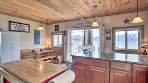Een keuken met houten kasten, een houten tafel en een bordje met de tekst 'SUMMER HOUSE'.