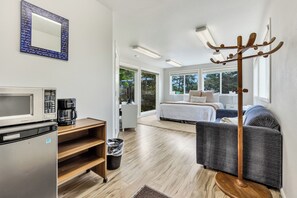 Habitación de hotel compacta con kitchenette, una cama, zona de estar y perchero.