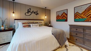 Ein Schlafzimmer mit einem Bett, einer Kommode, Wandbildern und einem an der Wand befestigten Schild.