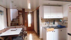 A compact kitchen with white cabinets, a sink, and a dining area with a table and chairs. - Small resin house (Arcachon)