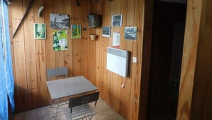A wooden-paneled room with a table and chairs, a radiator, and various photographs and notices on the walls. - Small resin house (Arcachon)