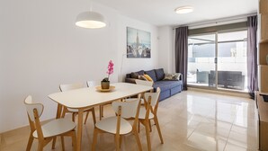 Una sala de estar moderna con comedor, que incluye un sofá, una mesa de centro y un cuadro en la pared.