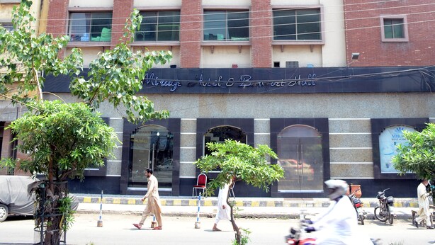 A multi-story building with a modern architectural design, featuring a prominent entrance with glass doors and a sign above. - Mirage Hotel (Lahore)