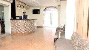 A reception area with a tiled counter, a sofa, and a television. - Mirage Hotel (Lahore)
