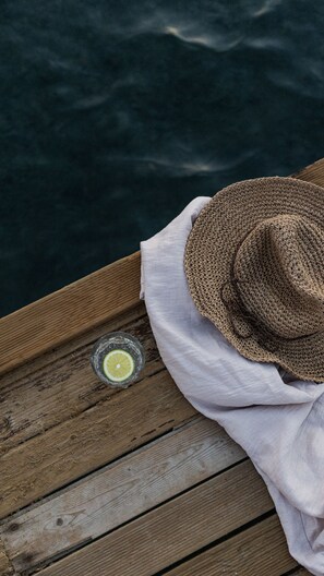 A wooden deck with a woven hat and a glass with a lime slice on it. - Kaju Rooms (Marmaris)