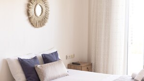 A neatly made bed with a white and beige bedspread, two pillows, and a remote control on a wooden nightstand. - Kaju Rooms (Marmaris)