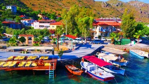A coastal village with clear waters, boats docked, and a row of houses with red roofs. - Kaju Rooms (Marmaris)