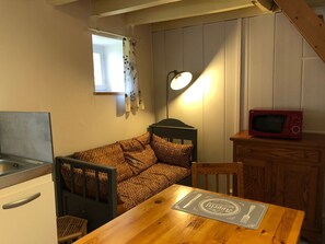 Et kompakt tekøkken med køleskab, mikroovn og et lille spisebord.