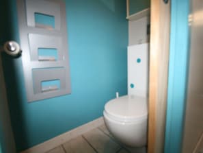 A compact bathroom with a toilet and door, featuring a tiled floor.
