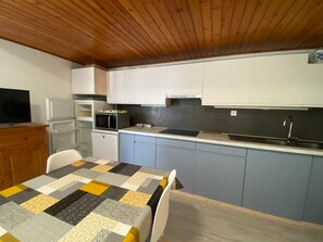 Efficient kitchen space with a dining area, featuring a microwave, dishwasher, and light cabinets.