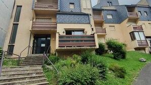 A multi-story residential building with a central entrance, balconies, and a small garden area. - T2 Bis Apartment for 6 People with Parking in Cauterets (Cauterets)