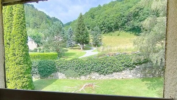 A view from a window overlooking a lush green landscape with a stone wall and a winding path. - T2 Bis Apartment for 6 People with Parking in Cauterets (Cauterets)