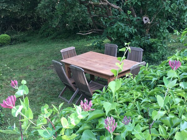 A wooden table with four chairs in a garden setting.