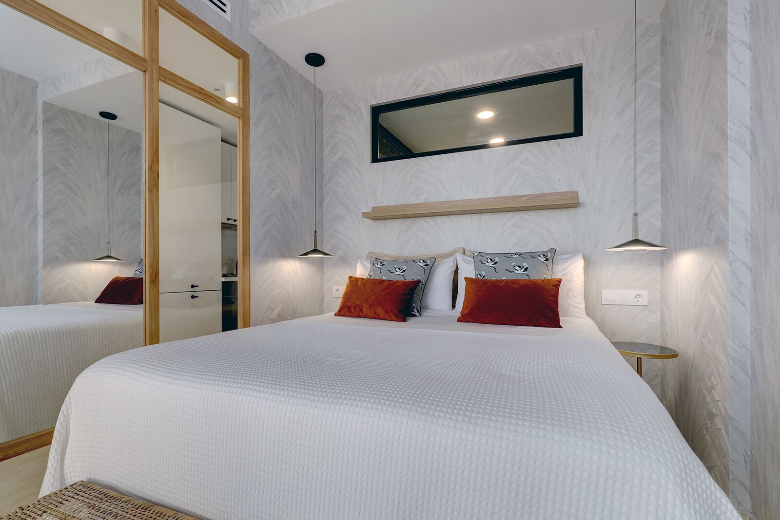 Un dormitorio moderno con dos camas, un espejo grande y lámparas de noche.