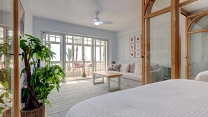 A spacious bedroom with a large bed, a wooden-framed sliding door, a dining area with a table and chairs, and a balcony with a view. - Ale Maison sotogrande port and beachfront private terrace sea view (San Roque)