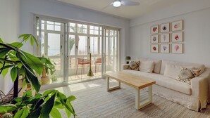 A spacious living room with a large sliding glass door leading to a balcony, a beige sofa, a wooden coffee table, and a ceiling fan. - Ale Maison sotogrande port and beachfront private terrace sea view (San Roque)