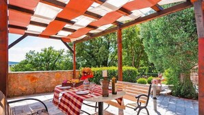 Un patio al aire libre con una mesa lista para comer, un banco y una estructura de pérgola.