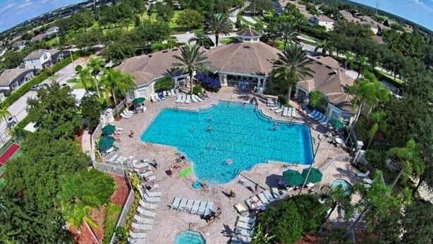 An aerial view of a resort with a large swimming pool surrounded by lounge chairs and palm trees. - Magic Escape- Themed Bedrooms, Pool/Spa, Game Room, Movie Theater! Near Disney! (Kissimmee)