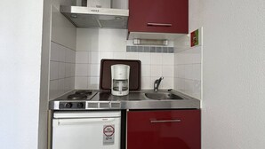 Una cocina compacta con lavavajillas Bosch, cafetera y fregadero.