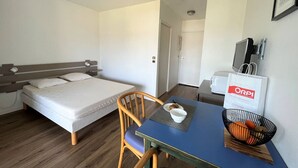 Una habitación de hotel con una cama, una mesa con un frutero, una silla y un televisor.
