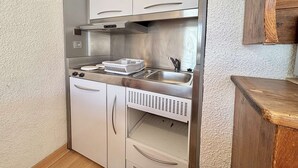 A compact kitchen with white cabinets, stainless steel appliances, and a wooden countertop. - Perfect ski studio, balcony, parking - Notre-Dame-de-Bellecombe (Notre-Dame-de-Bellecombe)