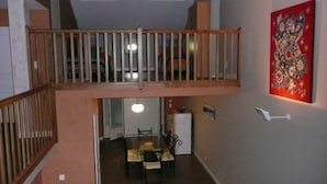 Eine Mehrstöckige Wohnung mit Essbereich, einem Balkon und einem roten Kunstwerk an der Wand.