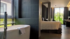 Une salle de bain moderne avec une baignoire, une douche et une grande fenêtre équipée de stores.