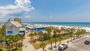 A beachside view of a hotel with a pool area, palm trees, and a clear view of the ocean.