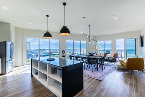 Eine moderne Küche mit Kochinsel, Essbereich mit Stühlen und einer Couch mit Meerblick.