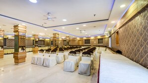 Un salón de conferencias con filas de sillas, un escenario y una pantalla grande.