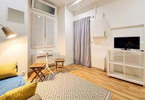 A modern living room with a bed, a small table, a TV, and a white cabinet. - New! N&J - LOU NISSART - Heart of the Old Town (Nice)
