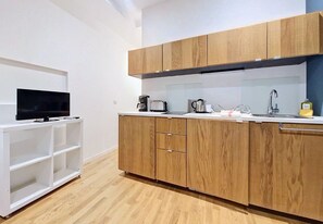 A modern kitchen with wooden cabinets, a white countertop, and a built-in TV on a white shelf. - New! N&J - LOU NISSART - Heart of the Old Town (Nice)