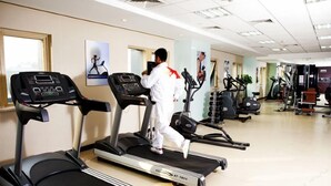 A gym with treadmills, a man walking on one, and exercise equipment in the background. - Guizhou Mansion (Beijing)