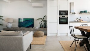 A modern living room with a sofa, TV, and a dining area with chairs and a table. - Town house in Silves (Silves)