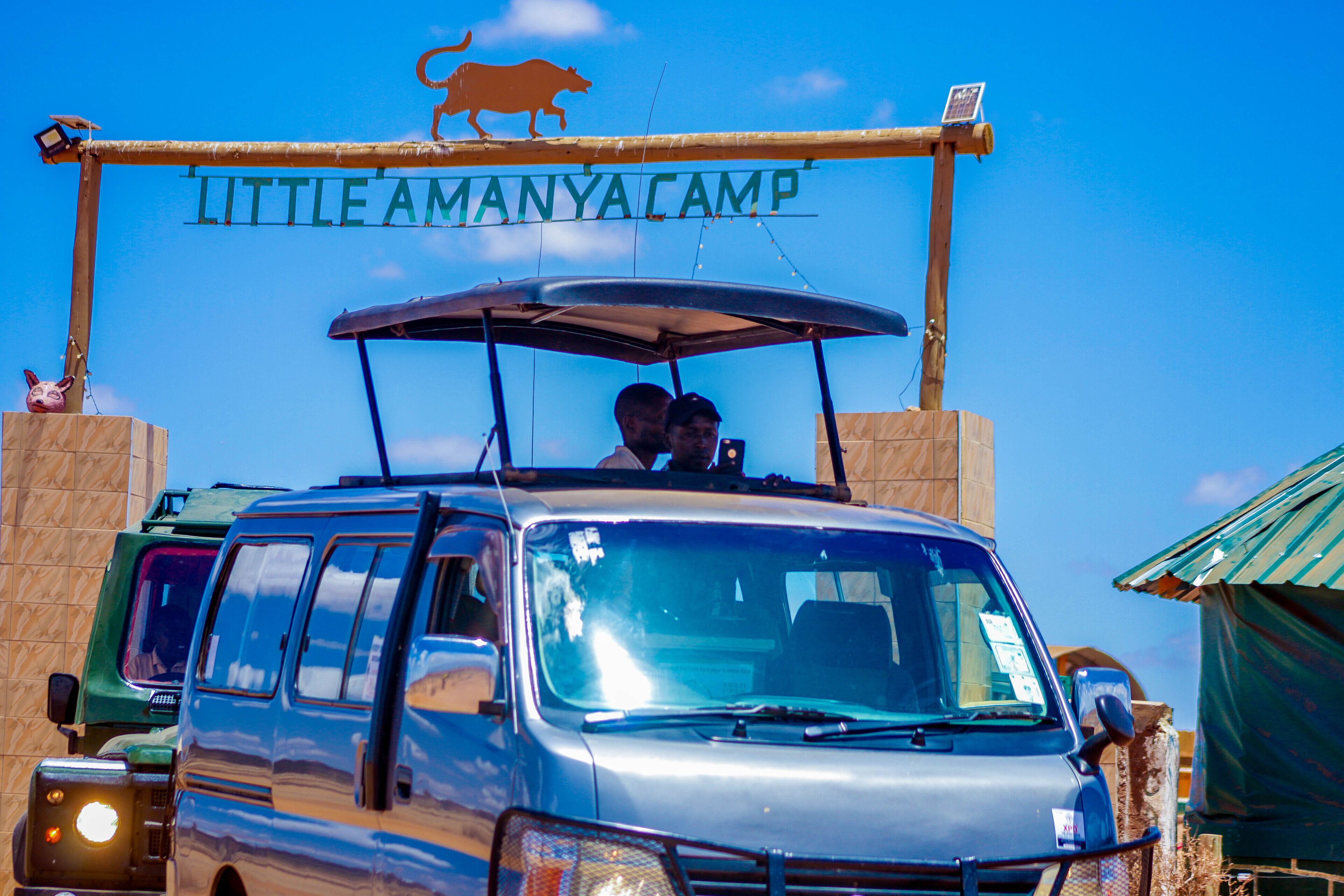 A van parked in front of a sign that reads "LITTLE AMANYA CAMP".