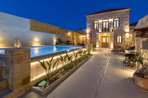 A stone house with a swimming pool, outdoor seating, and a well-lit patio area. - Amara Theta Living With Private Pool (Kissamos)