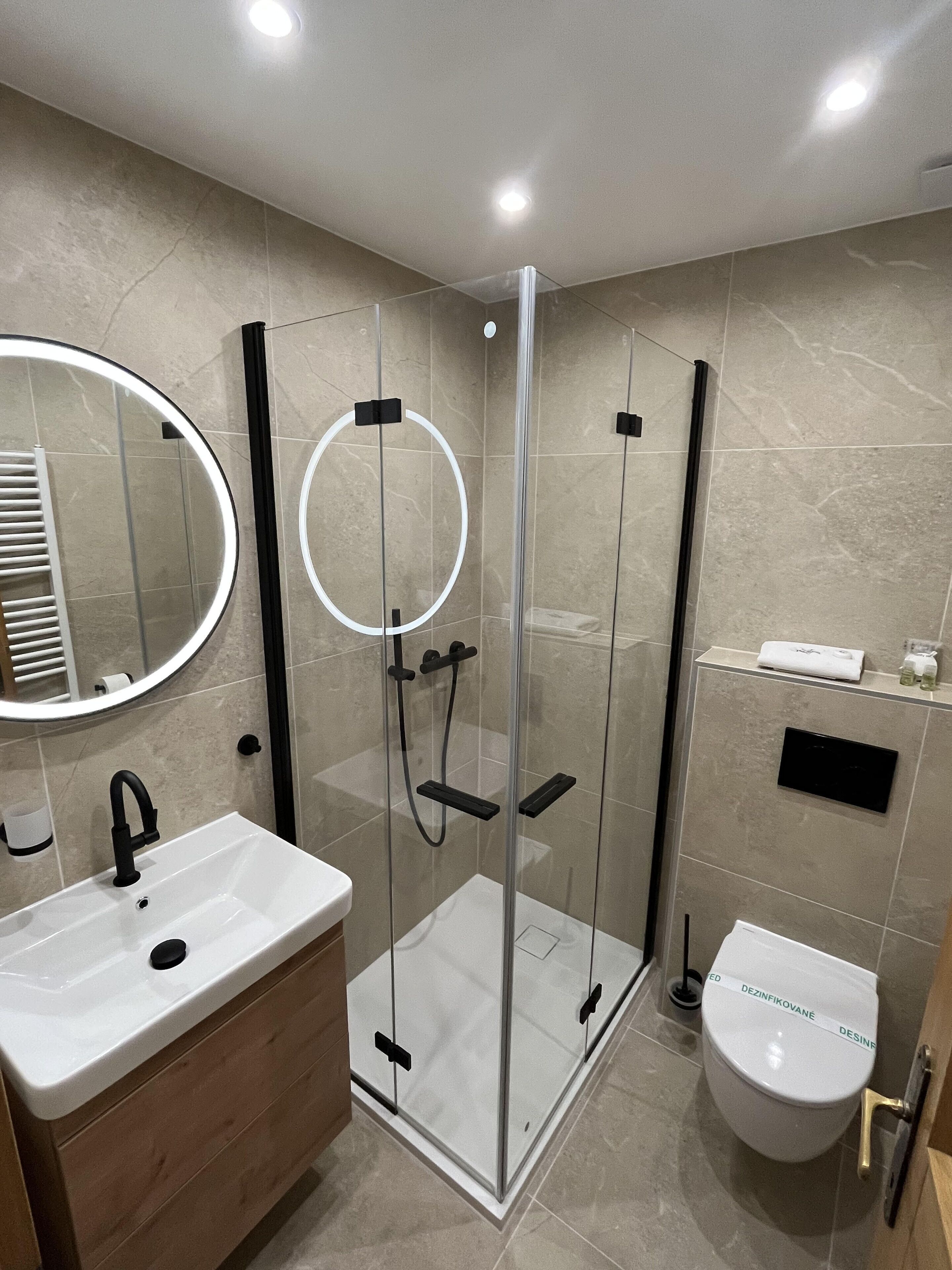 Un baño moderno con ducha envuelta en vidrio, lavamanos blanco y un inodoro.