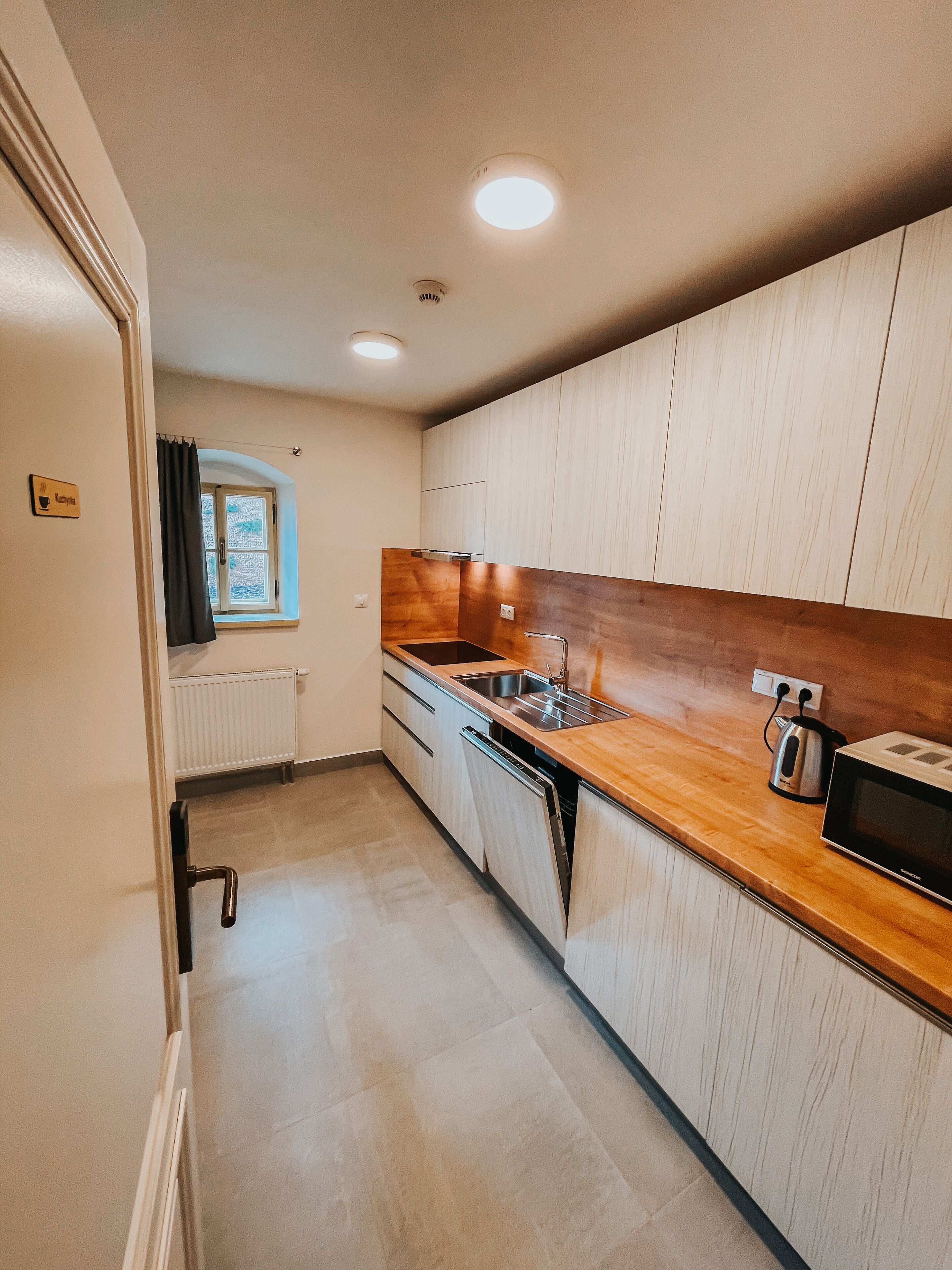 A compact kitchen with wooden cabinets, a stainless steel sink, and a microwave.