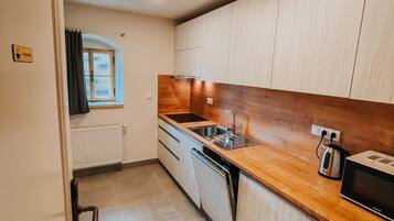 A compact kitchen with wooden cabinets, a stainless steel sink, and a microwave.