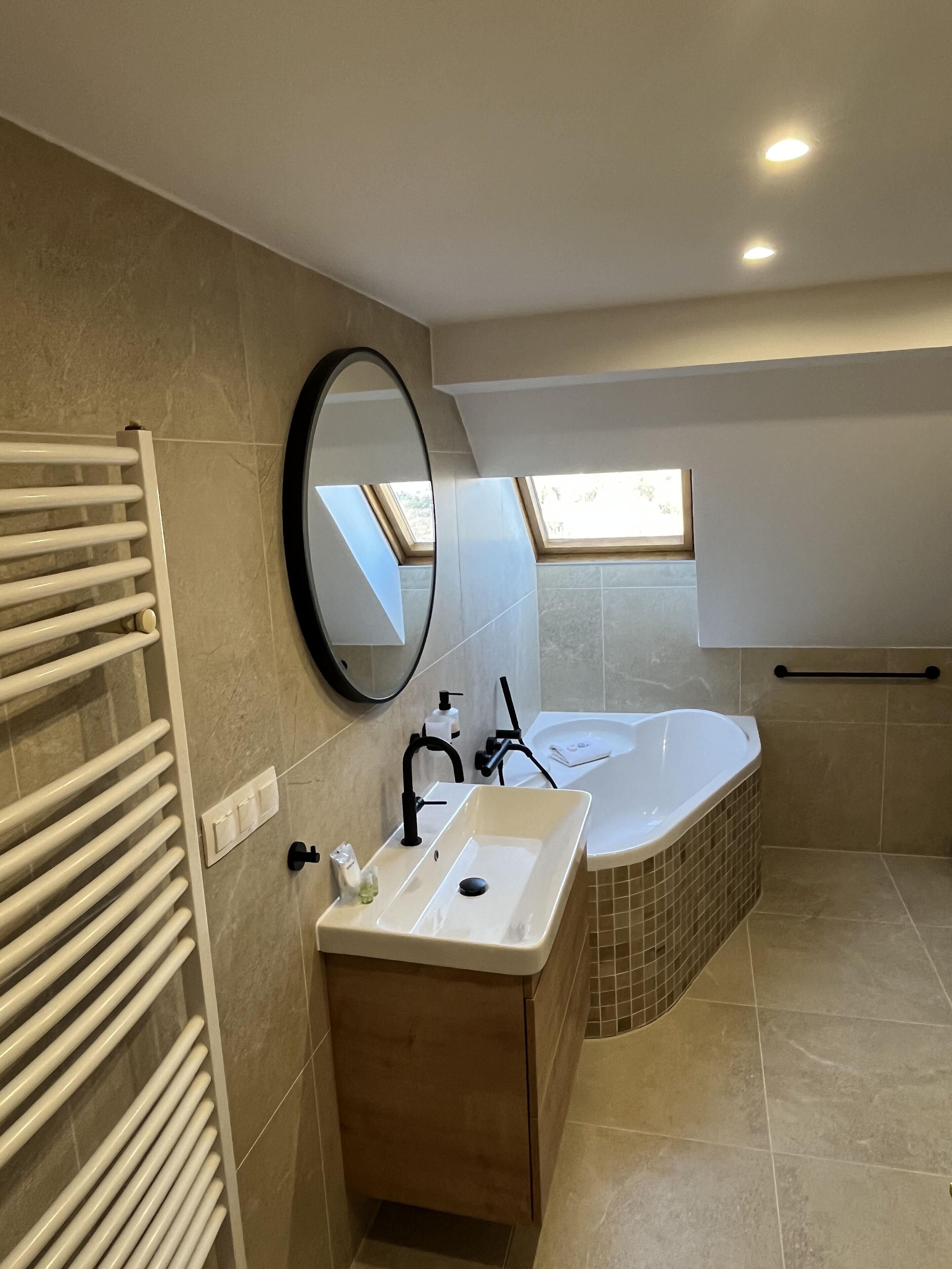 Ein modernes Badezimmer mit einer freistehenden Badewanne, einem Waschtisch, einem Handtuchhalter und einem Spiegel.