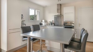 A modern kitchen with a dining table, chairs, and a built-in oven. - Charming house for 11 people in Sarzeau (Sarzeau)