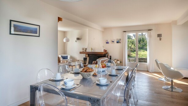 A dining area with a long table set for breakfast, clear chairs, and a view of the outdoors through a large window. - Charming house for 11 people in Sarzeau (Sarzeau)