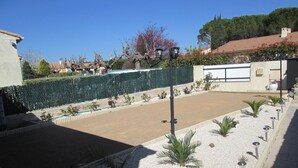 Une cour avec une zone pavée, de petites plantes et une clôture.