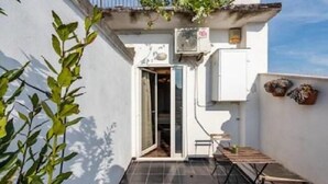 A small, enclosed balcony with a tiled floor, a sliding glass door, and a small table with chairs. - Cavour Room 5 Suite (Bari)