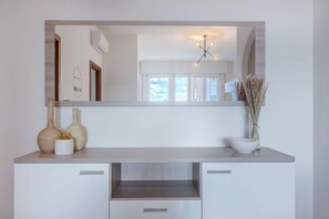 A modern bathroom with a large mirror, a light fixture, and a vase with dried plants. - GuestHost - Bright Apartment with a Terrace (Ferrara)