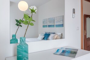 A bedroom with a bed, a bedside table, a vase with a plant, and wall art.