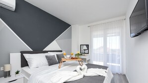 A modern bedroom with a bed, bedside table, and a TV mounted on the wall. - Villa Tia (Policnik)