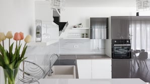 A modern kitchen with white cabinetry, a built-in oven, and a stainless steel refrigerator. - Villa Tia (Policnik)